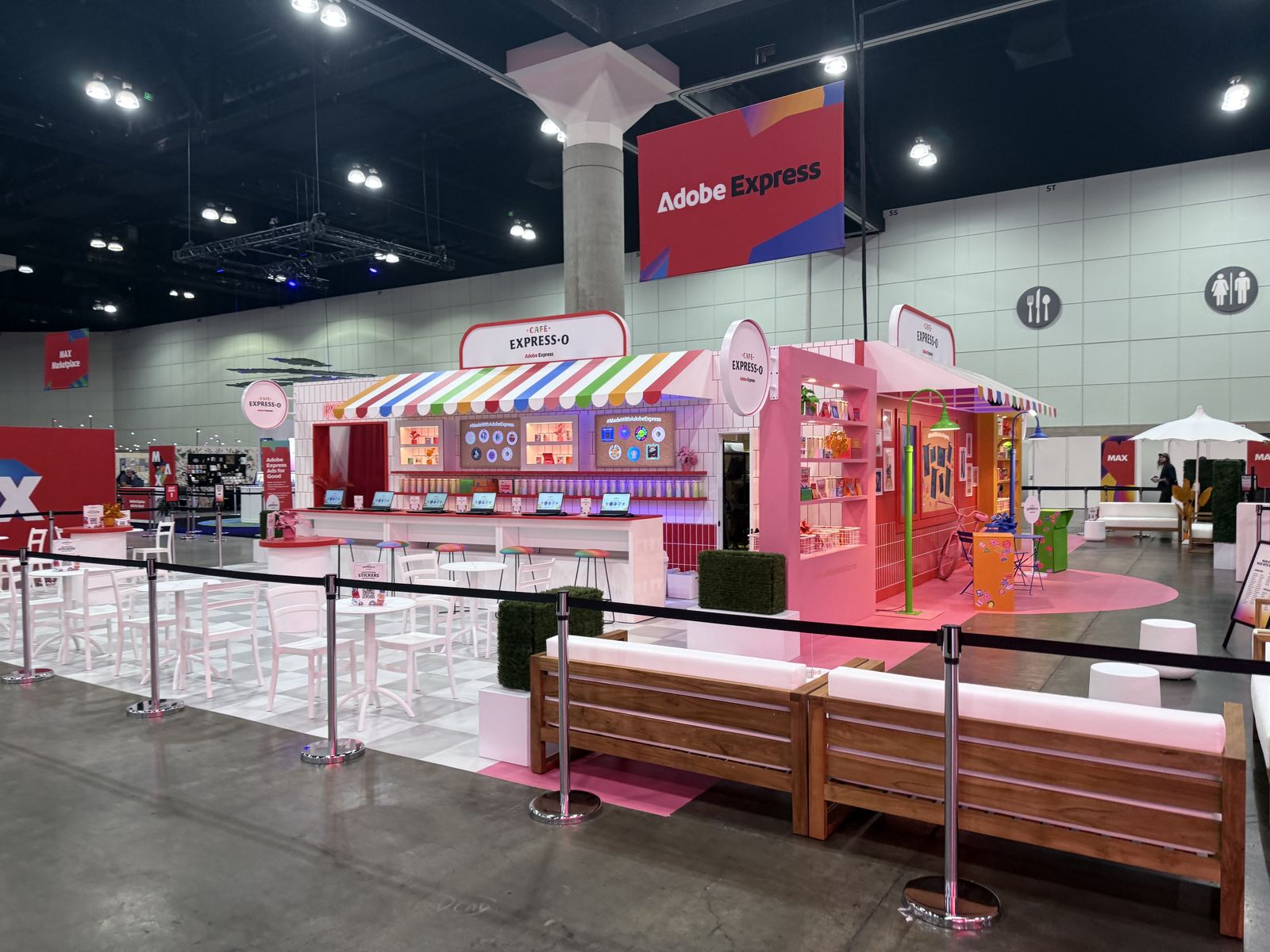 Large pink branded booth build with seating area on a convention center floor
